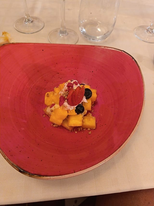 Postre de fruita amb nata i fruits rojos en un plat roig