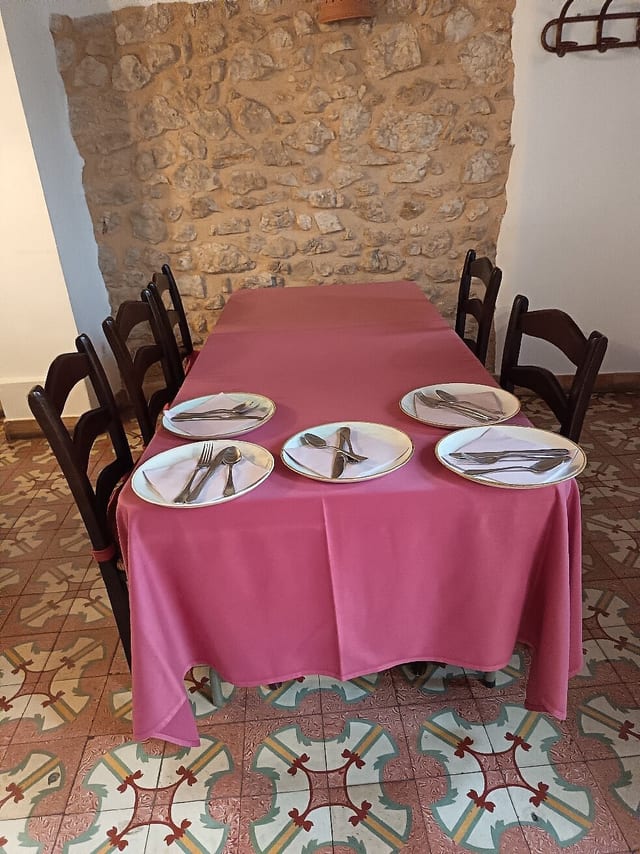 Taula parada amb estovalles rosades i cadires de fusta